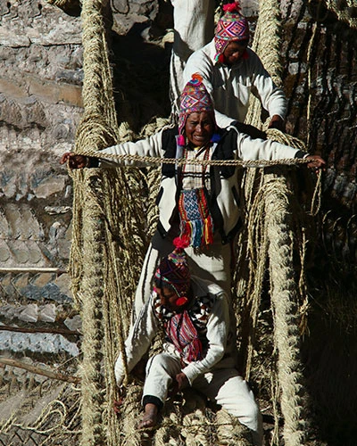 Walking Across Qeswachaka Bridge Peru Visitor walking across Q'eswachaka Bridge, the last Inca rope bridge in Peru, suspended high above the Apurímac River in the Andes.